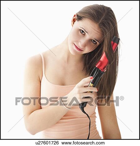 Stock Photograph - Studio portrait of young woman curling hair. Fotosearch