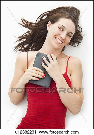 Stock Image - Studio portrait of young woman holding electronic organizer. Fotosearch
