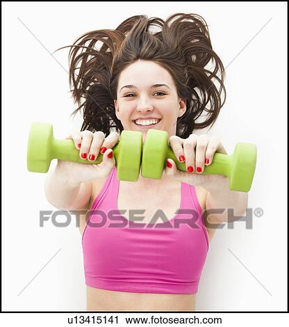 Studio portrait of young woman holding hand weights View Large Photo Image Stock Image - Studio portrait of young woman holding hand weights. Fotosearch