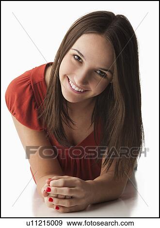 Studio portrait of young woman lying down, smiling View Large Photo Image Stock Photo - Studio portrait of young woman lying down, smiling. Fotosearch