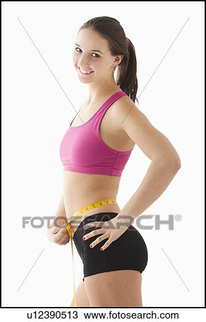 Studio portrait of young woman measuring waist View Large Photo Image Stock Image - Studio portrait of young woman measuring waist. Fotosearch