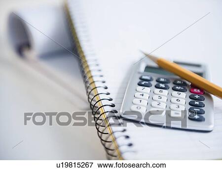 Stock Photo - Studio shot of calculator and pencil on notebook. Fotosearch
