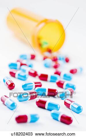 Stock Image - Studio shot of capsules spilling from bottle. Fotosearch