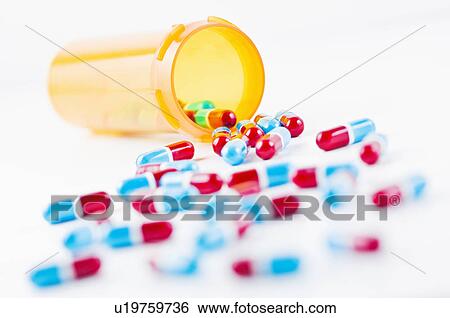 Stock Photograph - Studio shot of capsules spilling from bottle. Fotosearch