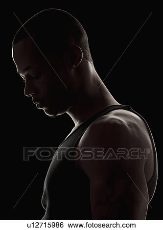 Stock Photograph - Studio shot of muscular young man wearing tank top. Fotosearch