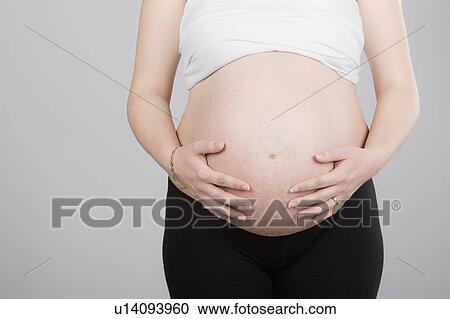 Stock Image - Studio shot of pregnant woman. Fotosearch