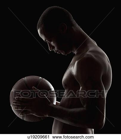 Stock Image - Studio shot of shirtless man holding basketball. Fotosearch