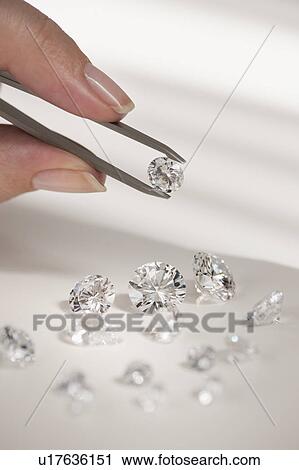 Stock Image - Studio shot of woman holding diamonds. Fotosearch