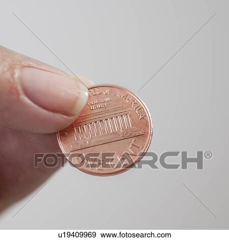 Stock Photo - Studio shot of woman holding one cent coin. Fotosearch