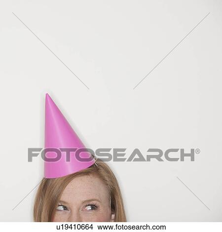 Picture - Studio shot of woman wearing pink party hat. Fotosearch