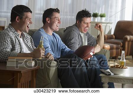 Three men watching television View Large Photo Image Stock Photo - Three men watching television. Fotosearch