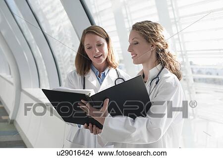 Picture - Two female doctors reading record. Fotosearch