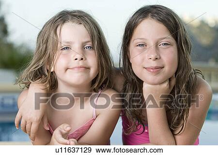 Stock Photo - Two girls (6-7, 8-9) embracing. Fotosearch