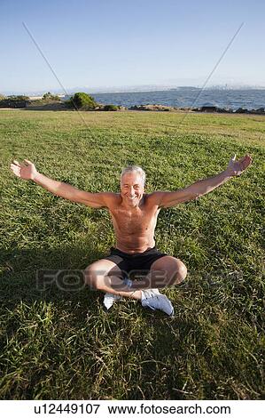 Stock Photo - USA, California, Berkeley, Senior man sitting cross-legged on grass. Fotosearch