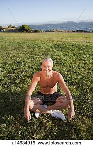 Stock Photograph - USA, California, Berkeley, Senior man sitting cross-legged on grass. Fotosearch
