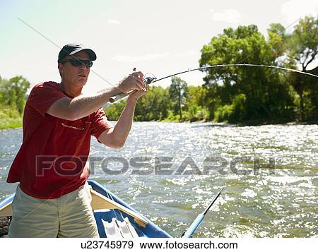 Stock Photo - USA, Colorado, Man fly-fishing from boat. Fotosearch