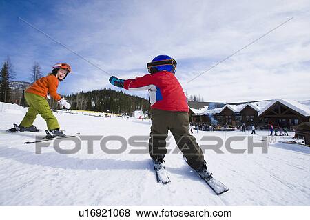 Stock Photo - USA, Montana, Whitefish, Boy (4-5) and girl (8-9) skiing. Fotosearch