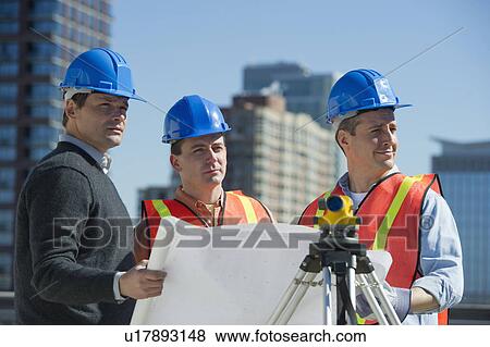 Stock Photo - USA, New Jersey, Jersey City, construction workers reading blueprint. Fotosearch