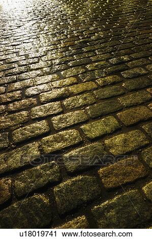 Stock Image - USA, New York, New York City, close up of cobblestone street at night. Fotosearch