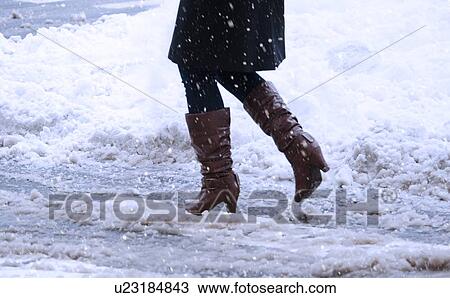 Stock Image - USA, New York, New York City, close up of woman's legs walking in winter slush. Fotosearch