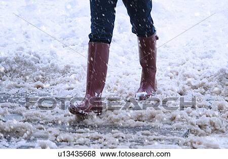 Stock Photo - USA, New York, New York City, close up of woman's legs walking in winter slush. Fotosearch