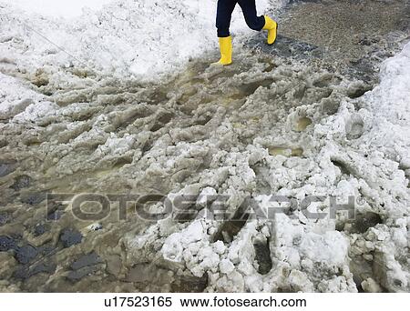 Stock Photography - USA, New York, New York City, legs of person in yellow rubber boots walking in slush. Fotosearch