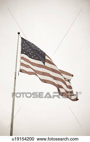 Stock Image - USA, Pennsylvania, American flag flying on mast. Fotosearch