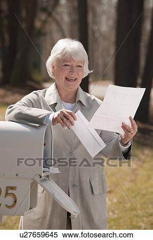 Stock Photography - USA, Virginia, Richmond, senior woman reading letters by mailbox. Fotosearch