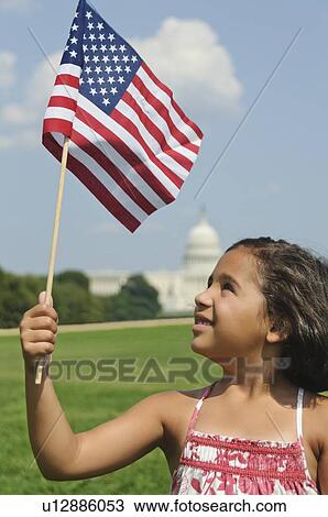Stock Image - USA, Washington DC, girl (10-11) with US flag in front of Capitol Building. Fotosearch
