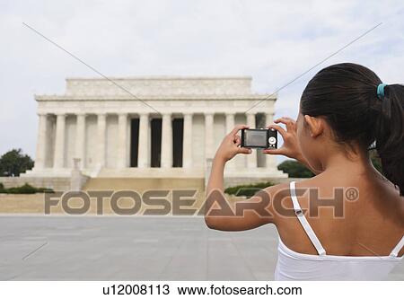 Stock Image - USA, Washington DC, girl (6-7) photographing Lincoln Memorial. Fotosearch