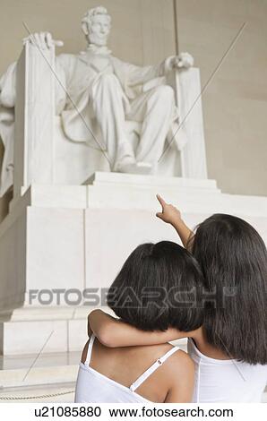 Stock Image - USA, Washington DC, Lincoln Memorial, two girls (10-11] looking at Lincoln statue. Fotosearch
