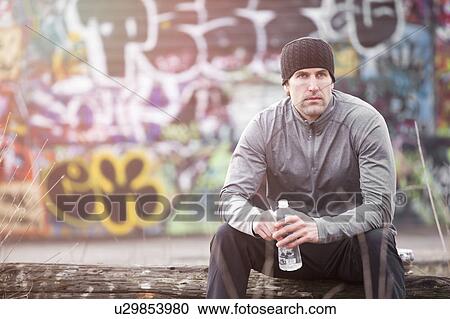 Stock Image - USA, Washington, Seattle, man in workout wear in front of graffiti wall. Fotosearch