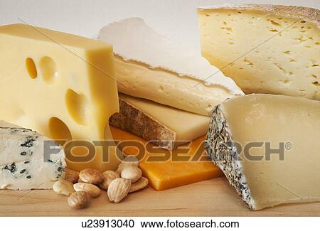Stock Image - Various cheeses on chopping board. Fotosearch