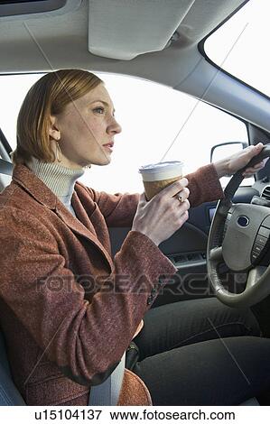 Stock Photo - Woman driving car and drinking coffee. Fotosearch