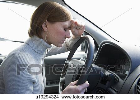 Picture - Woman driving car looking upset. Fotosearch