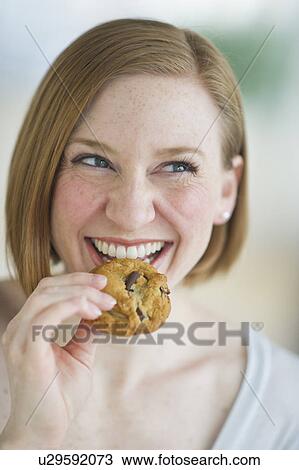 Stock Image - Woman eating cookies. Fotosearch