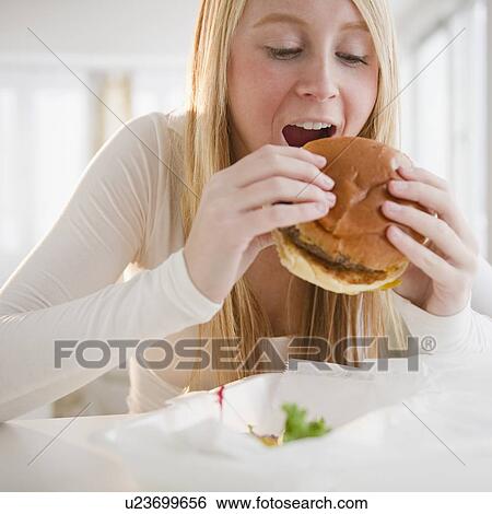 Stock Photograph - Woman eating hamburger. Fotosearch