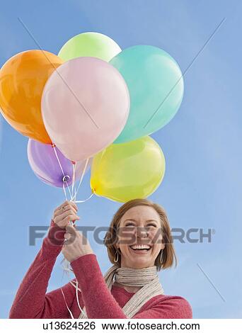 Stock Photograph - Woman holding bunch of balloons. Fotosearch