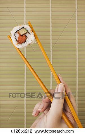 Woman holding sushi by chopsticks View Large Photo Image Stock Image - Woman holding sushi by chopsticks. Fotosearch