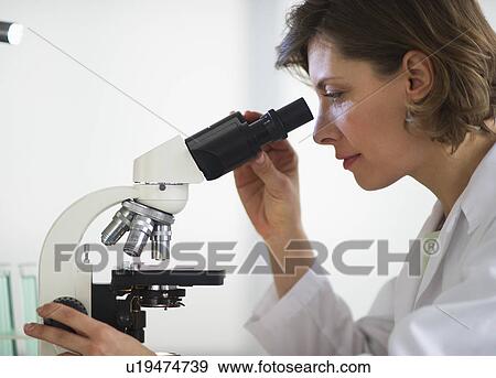 Stock Photo - Woman in laboratory looking through microscope. Fotosearch