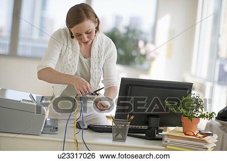 Stock Photograph - Woman installing router at home office. Fotosearch