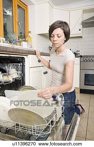Stock Image - Woman loading dishwasher. Fotosearch