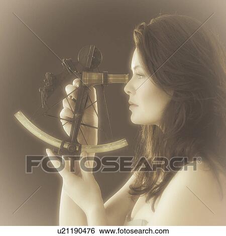 Stock Photograph - Woman looking through antique sextant, world map in background. Fotosearch