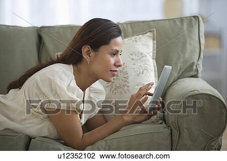 Woman lying on sofa and using digital tablet View Large Photo Image Stock Image - Woman lying on sofa and using digital tablet. Fotosearch