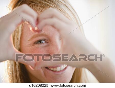 Stock Photography - Woman making heart shape with fingers. Fotosearch