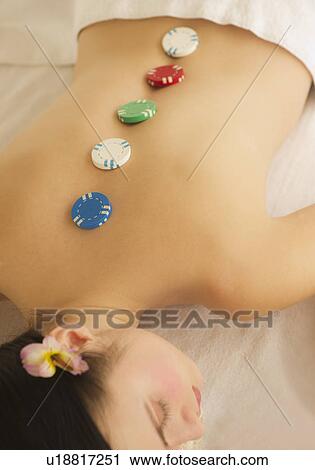 Stock Image - Woman on massage table with hot chips on her back. Fotosearch