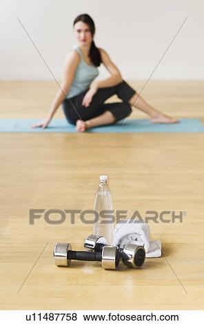 Woman on mat with dumbbells in foreground View Large Photo Image Stock Photo - Woman on mat with dumbbells in foreground. Fotosearch
