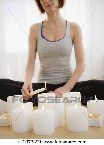 Stock Photo - Woman preparing for meditation and igniting candles. Fotosearch