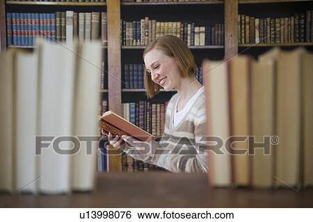 Stock Photograph - Woman reading book in library. Fotosearch