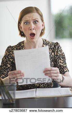 Woman reading document looking surprised View Large Photo Image Stock Photo - Woman reading document looking surprised. Fotosearch